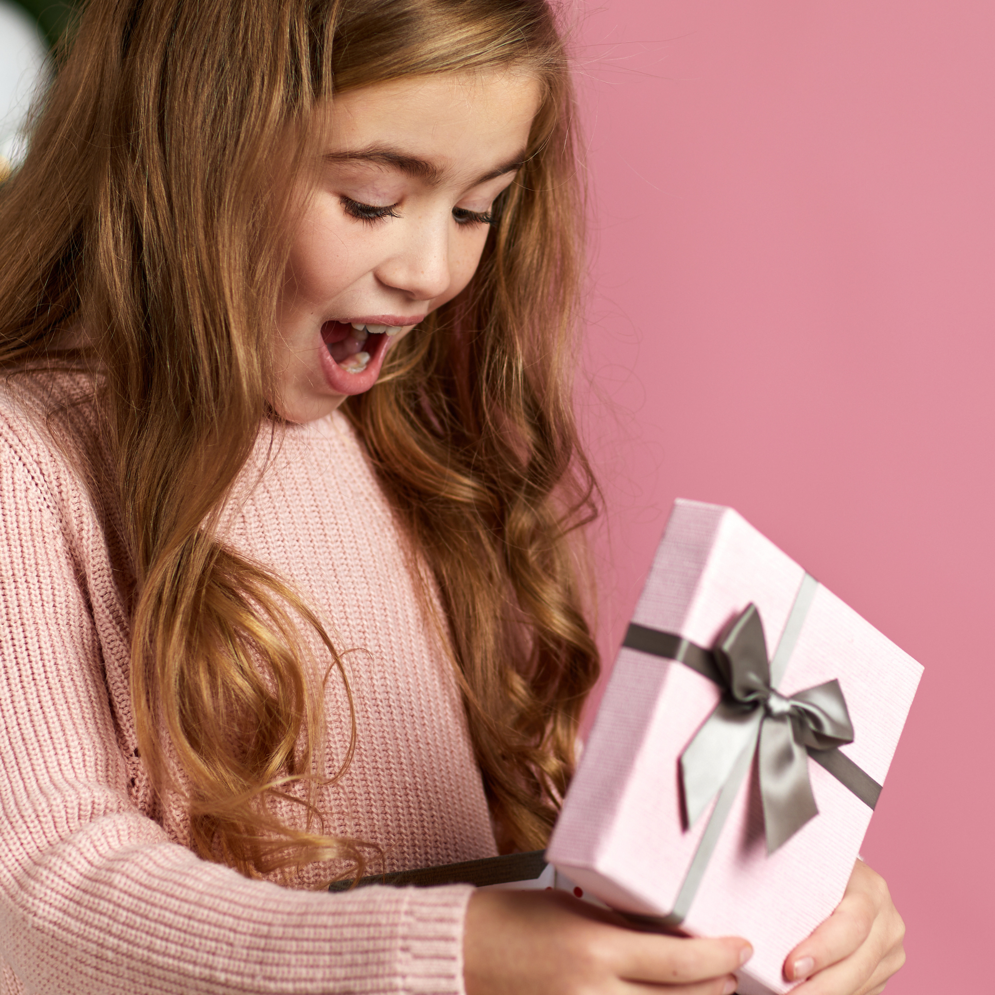 A girl looking surprised as she holds a gift- a teacher gift or mommy gift of a self published personalized storybook.